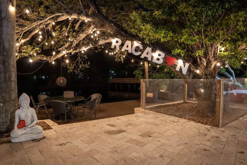 Waterfront patio beneath a tree and warm string lights at night