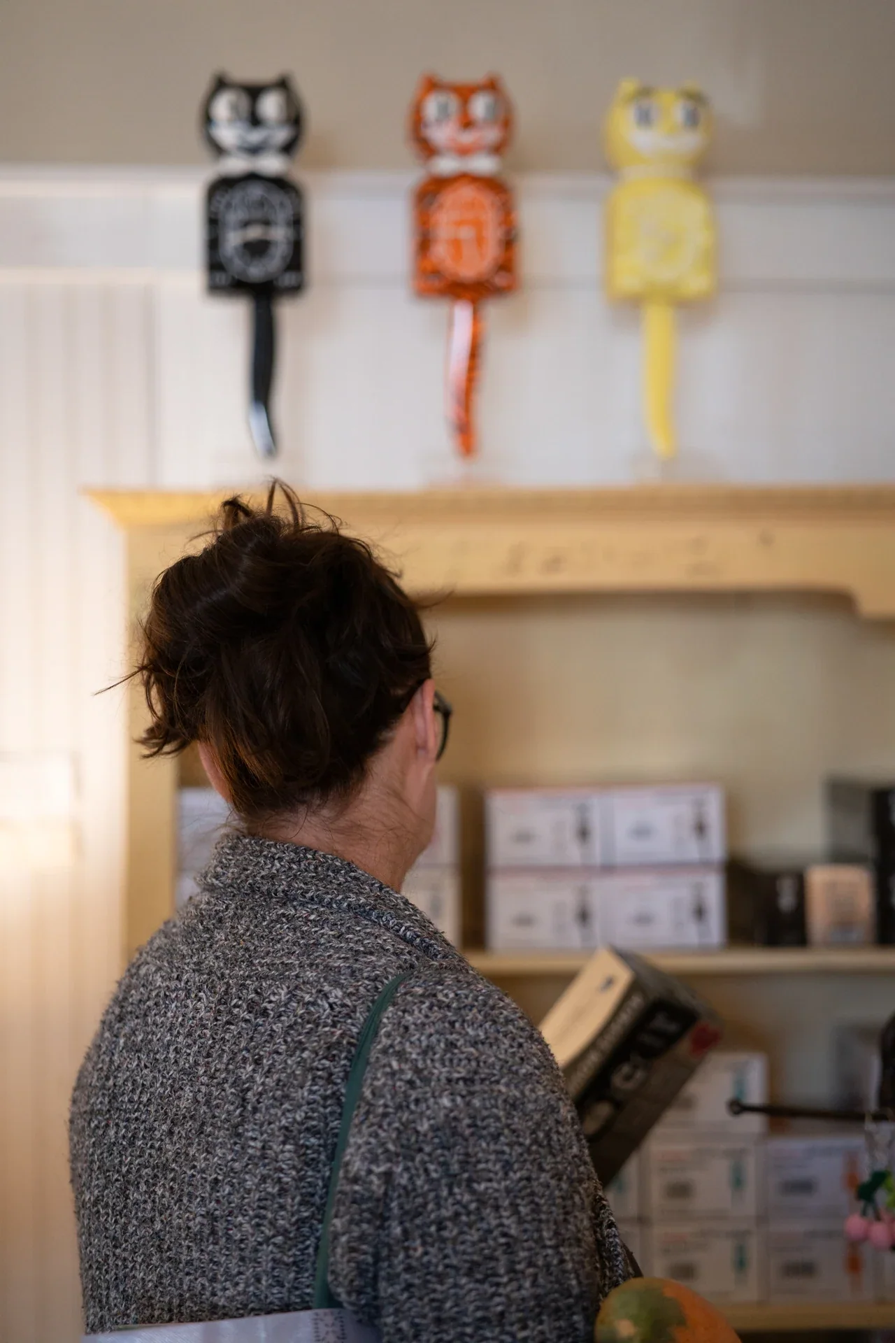 A person at an indoor counter beneath a wall display of small objects