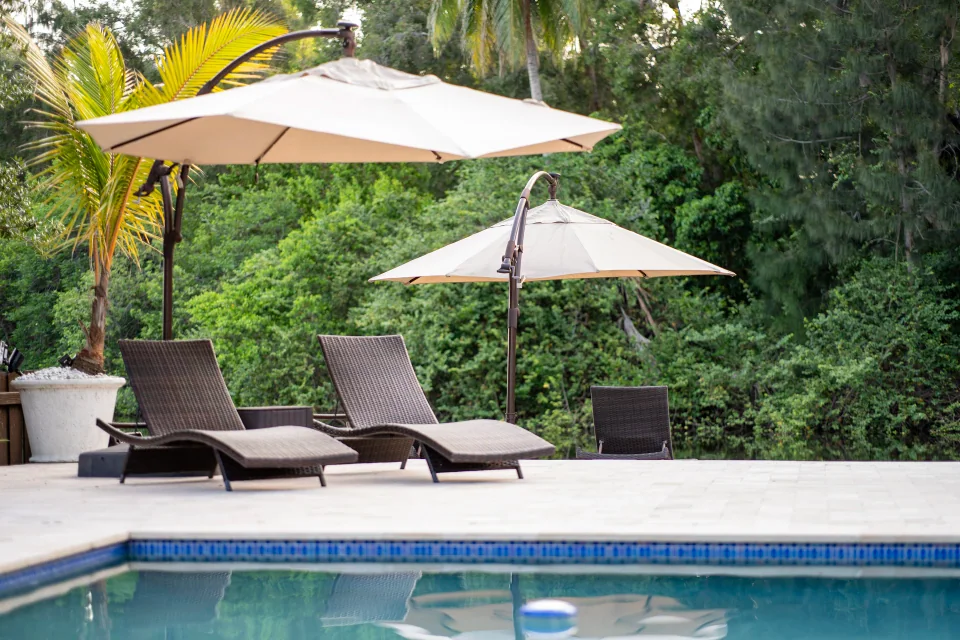 Lounge chairs under large umbrellas beside a swimming pool
