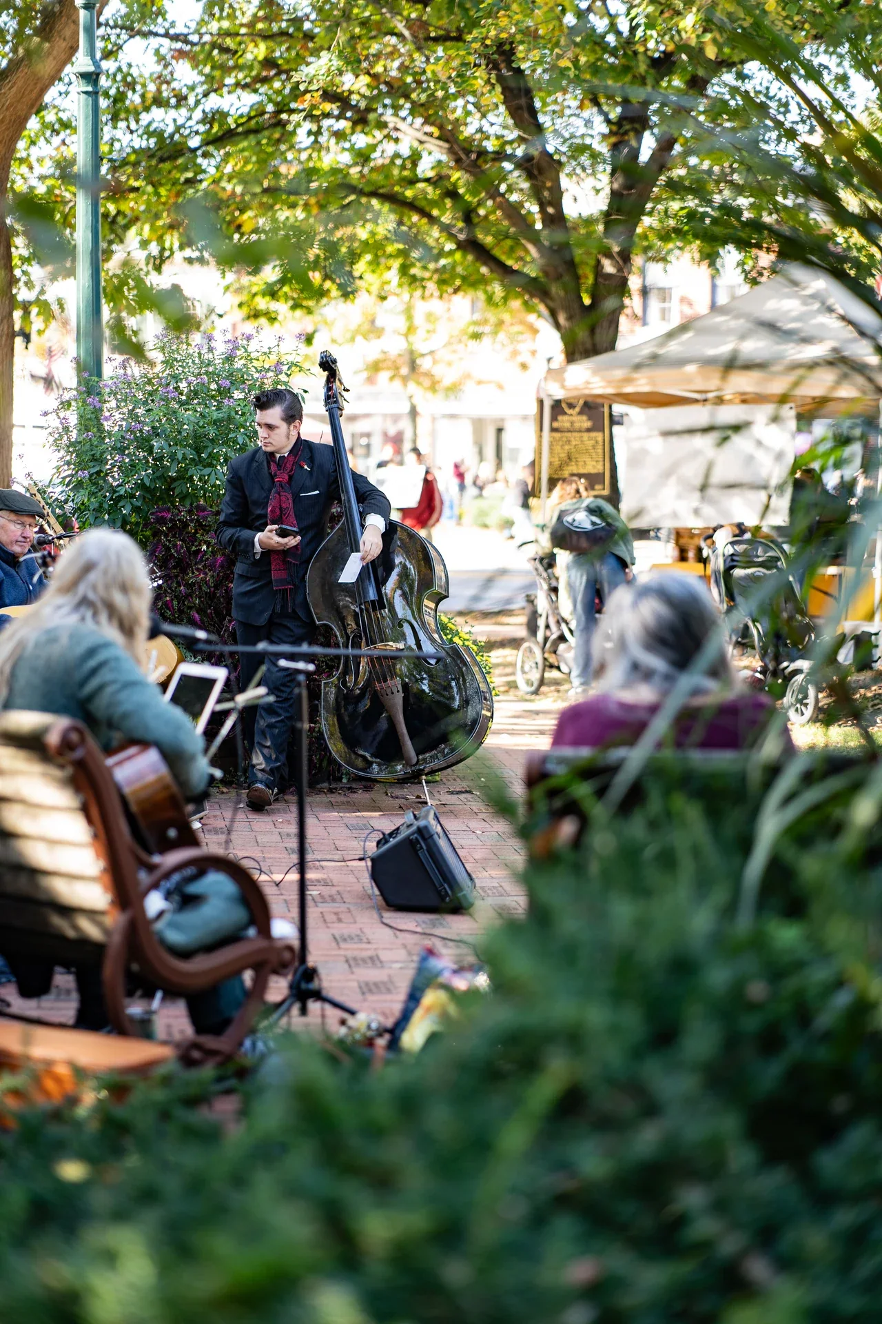 A small group of musicians performing beside an autumn market walkway
