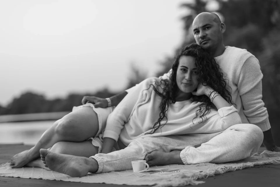 Couple reclining together beside a lake, photographed in black and white