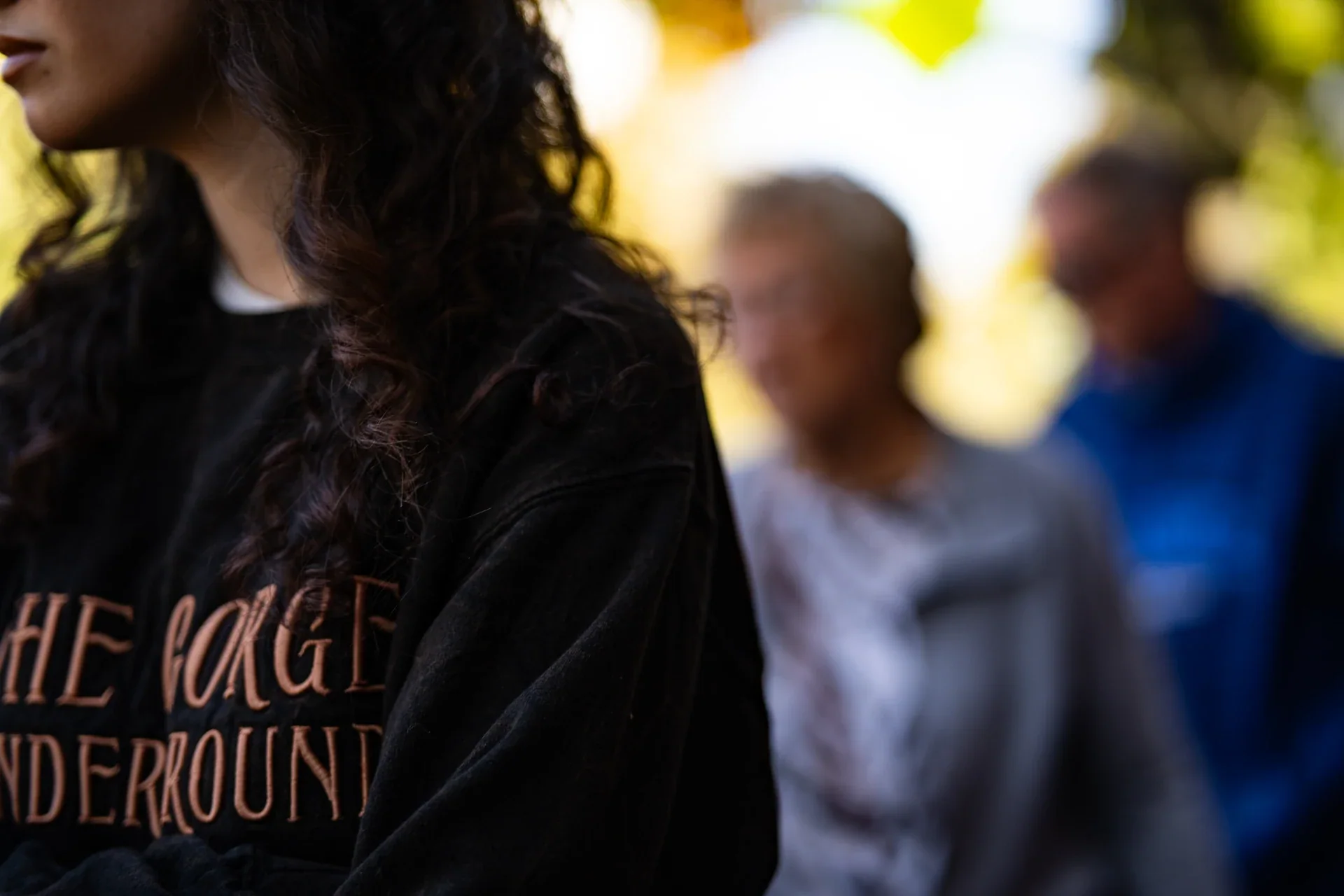A close view of a shopper wearing a dark printed shirt, with the market beyond