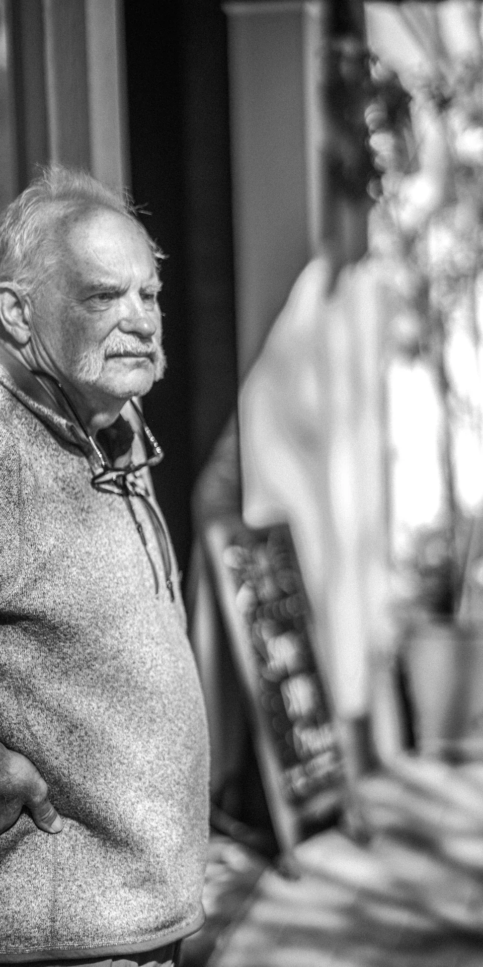 An older person in profile along the sidewalk, in black and white