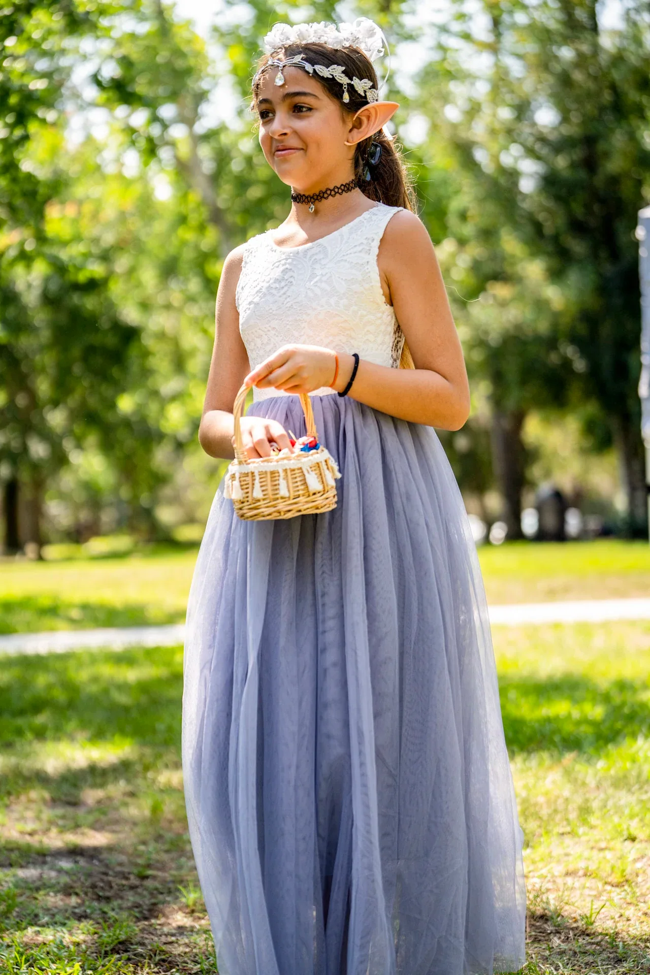 A child in a lilac dress holding a flower basket outdoors