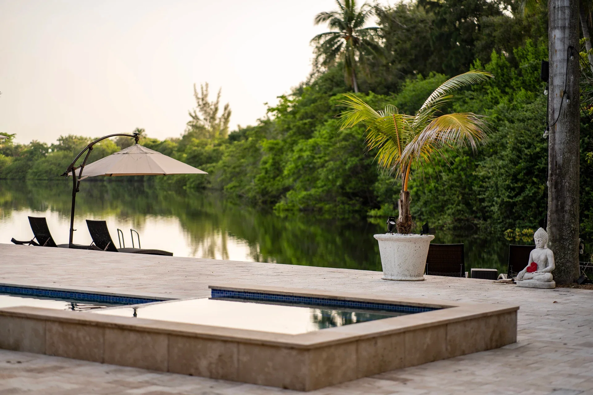 A pool overlooking a lake, surrounded by tropical plants