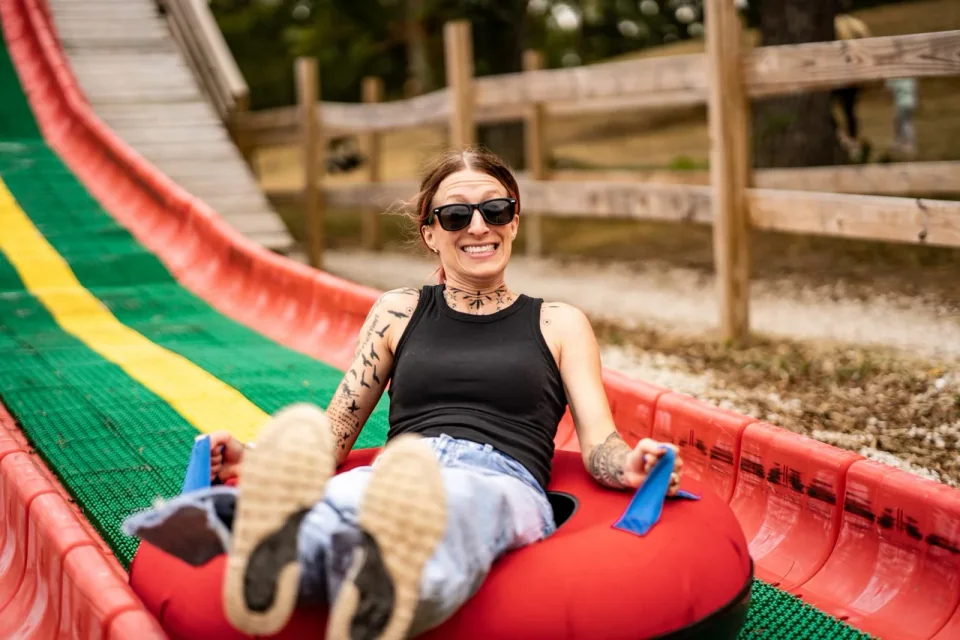 A person laughing while seated on a colorful playground slide