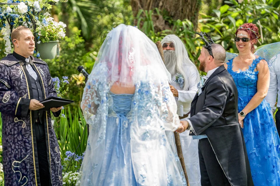 Outdoor wedding ceremony showing the couple, officiant, and attendants in a garden setting