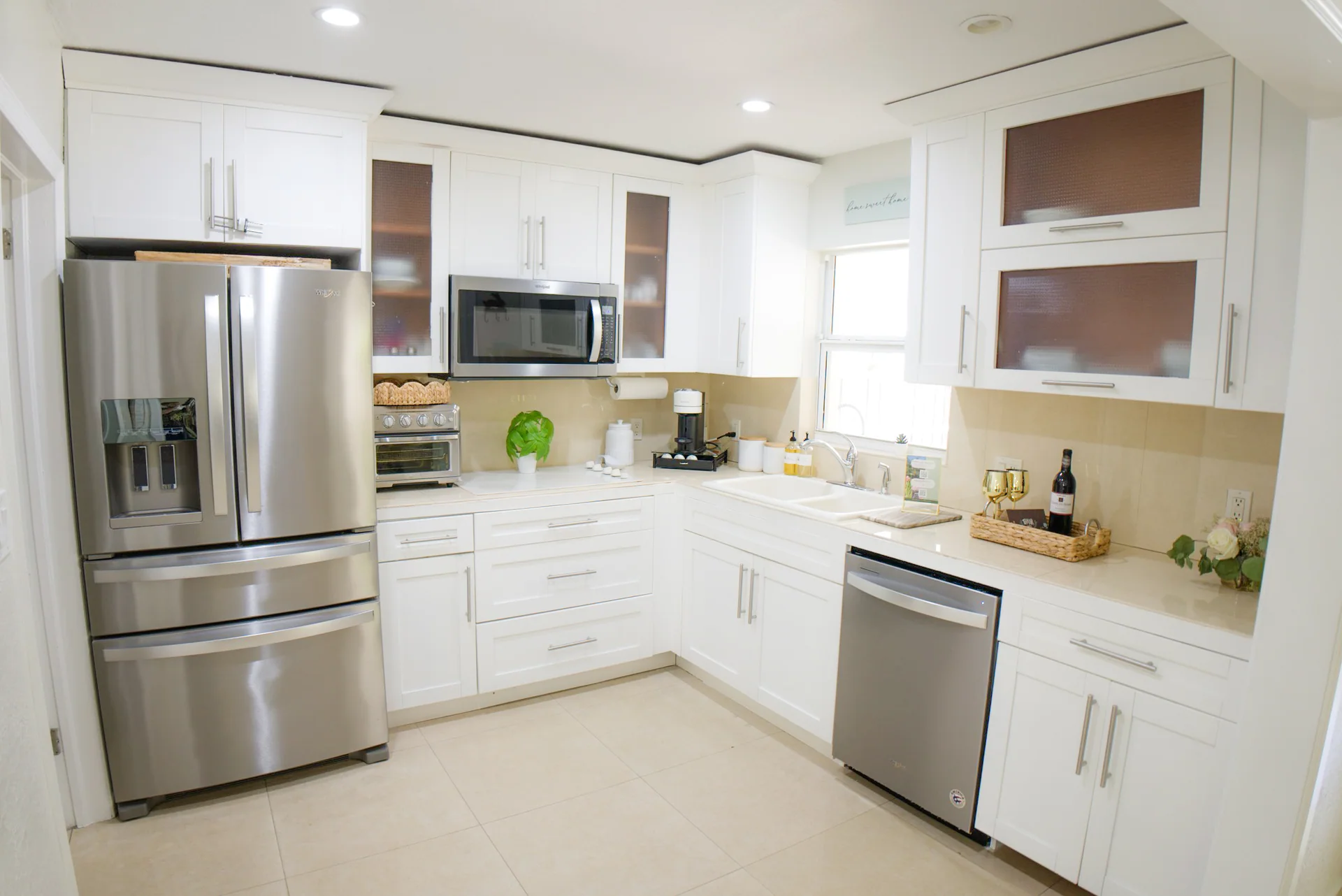 White residential kitchen with stainless steel appliances and warm neutral finishes