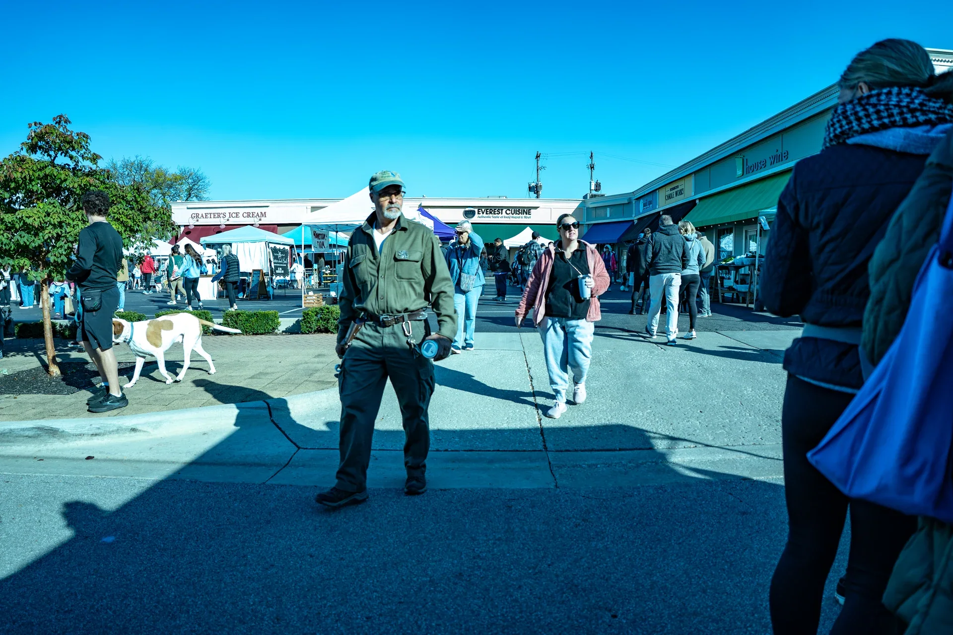 Shoppers walking between outdoor stalls and tents at the farmers market