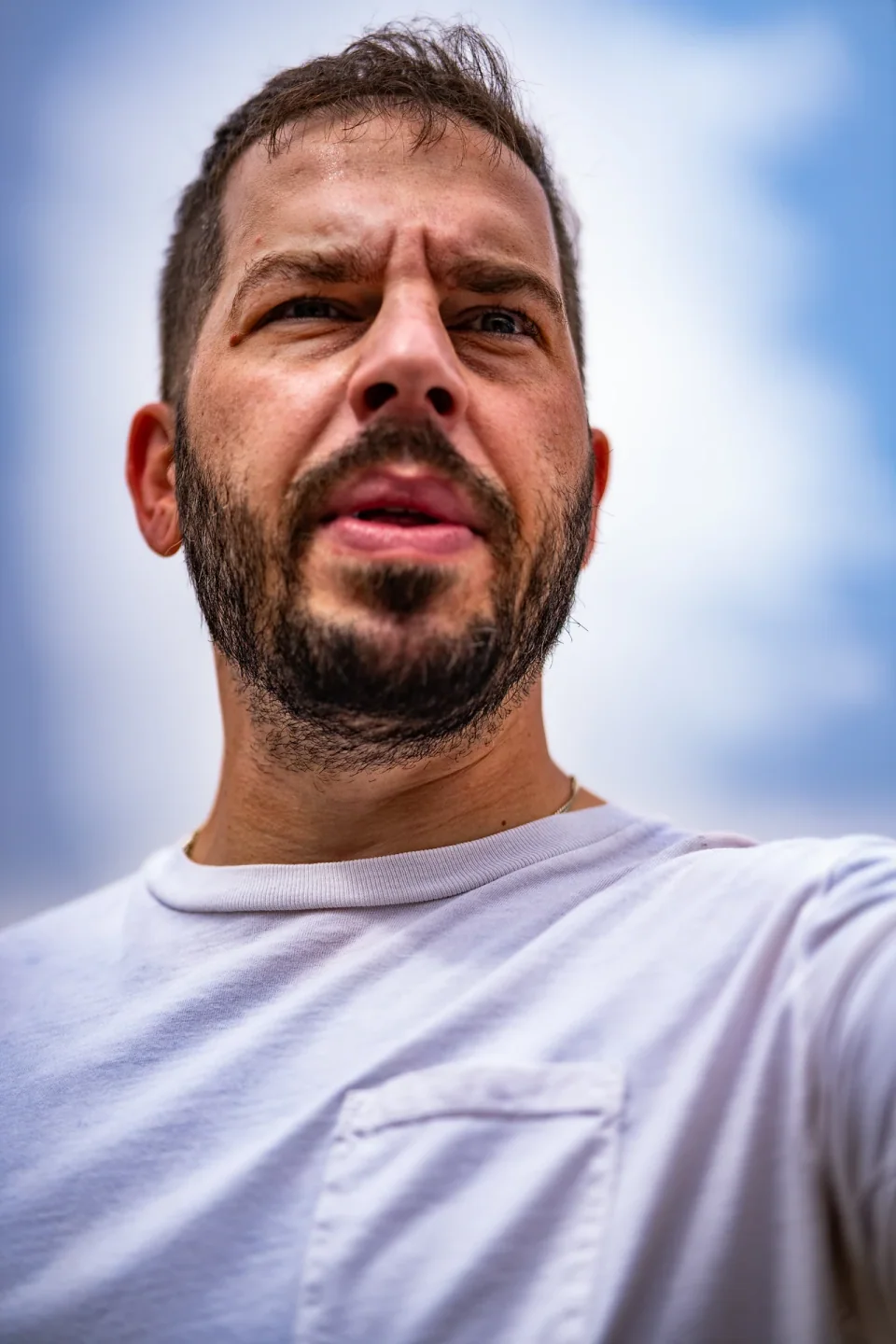 Low-angle portrait of a bearded person looking into the distance