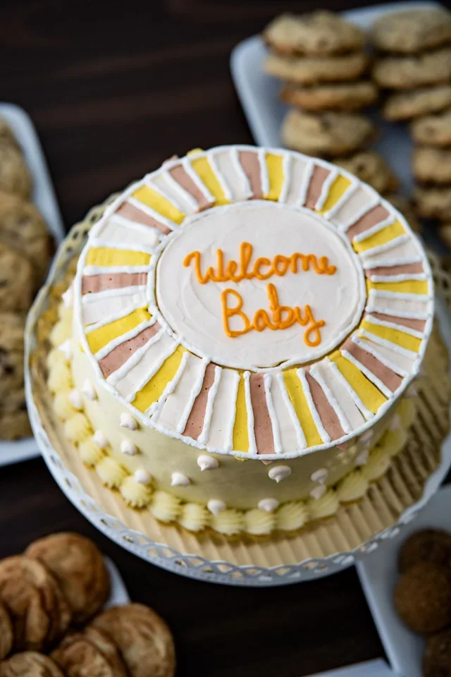 A decorated round cake with a Welcome Baby message
