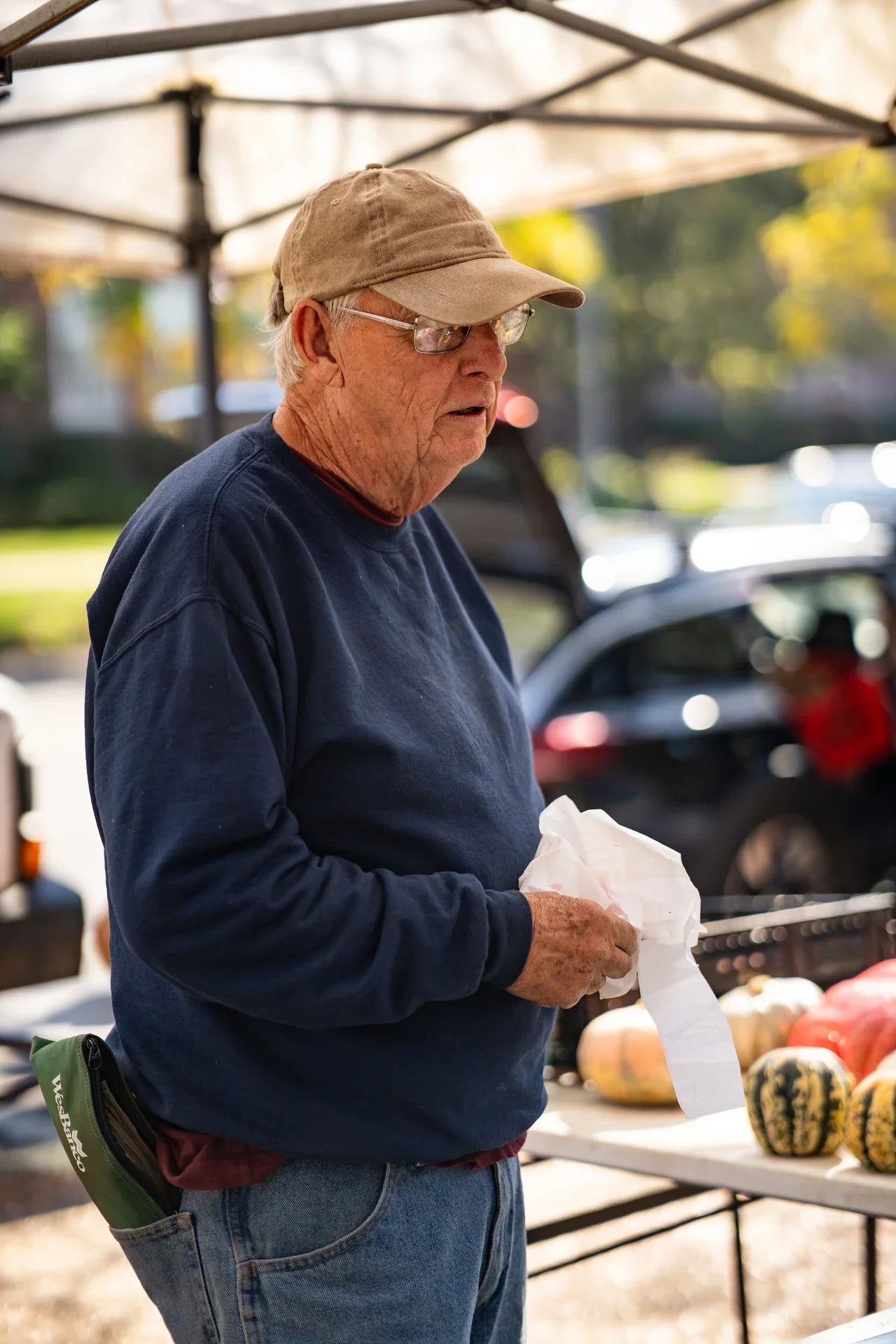 A market vendor standing beside a table of autumn produce
