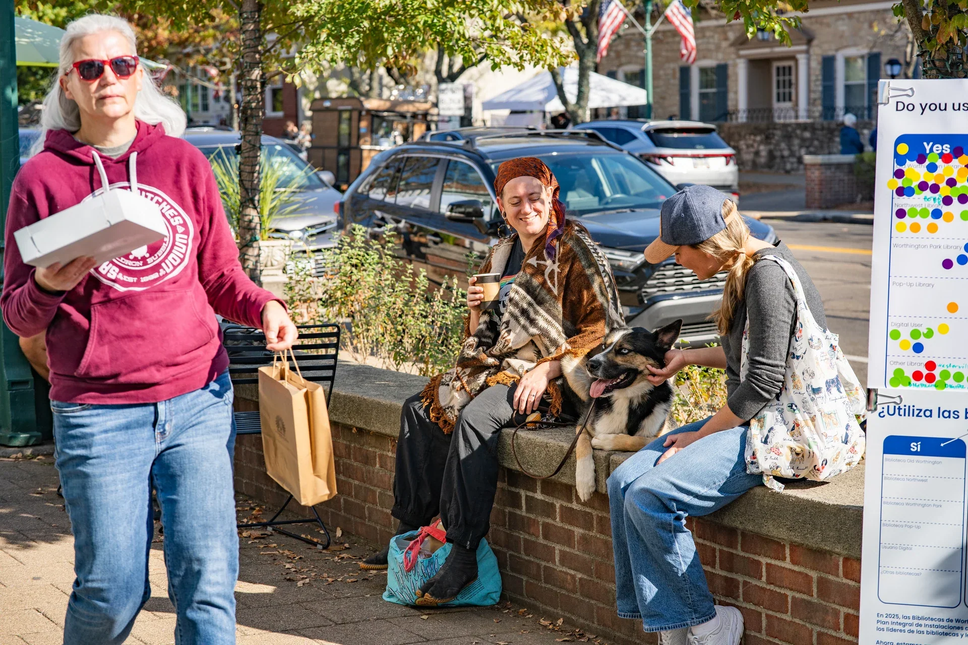 Market visitors resting and walking beside a low brick wall