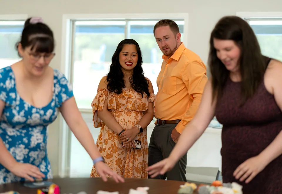 Parents-to-be watching guests play a baby shower game