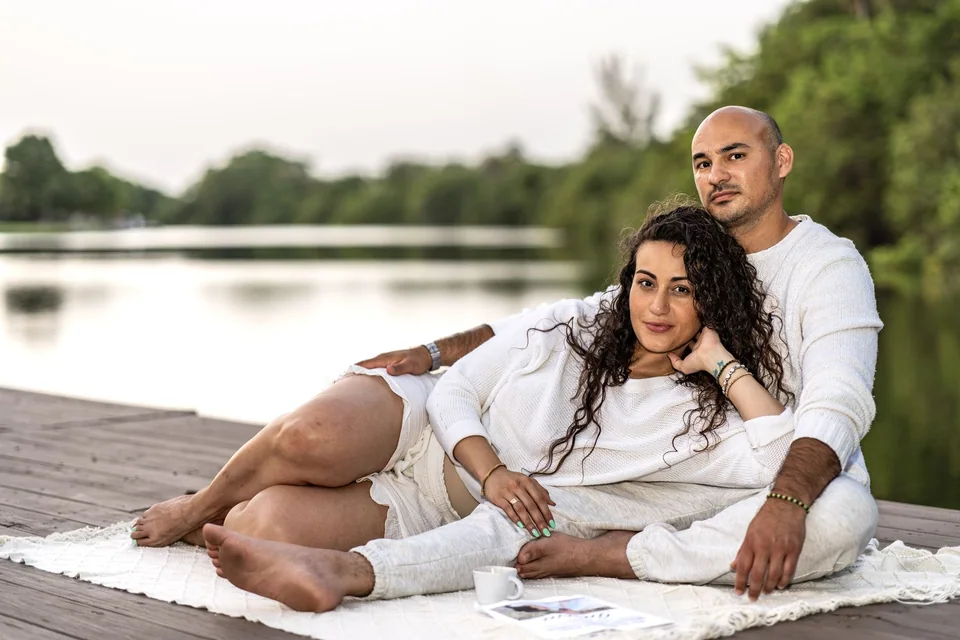 Couple sitting close together on a dock beside the lake