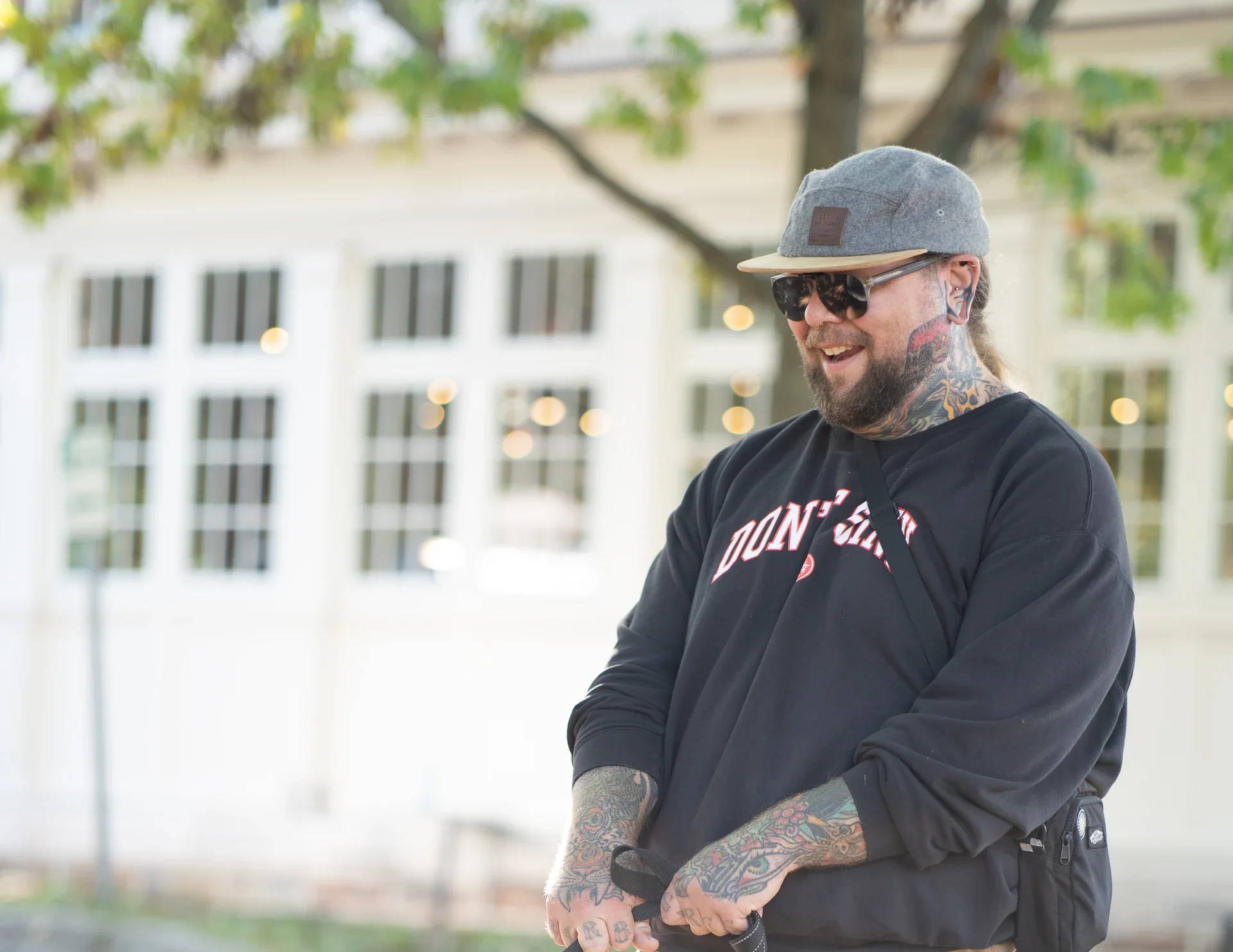 A person wearing a cap and sunglasses on a sunny sidewalk