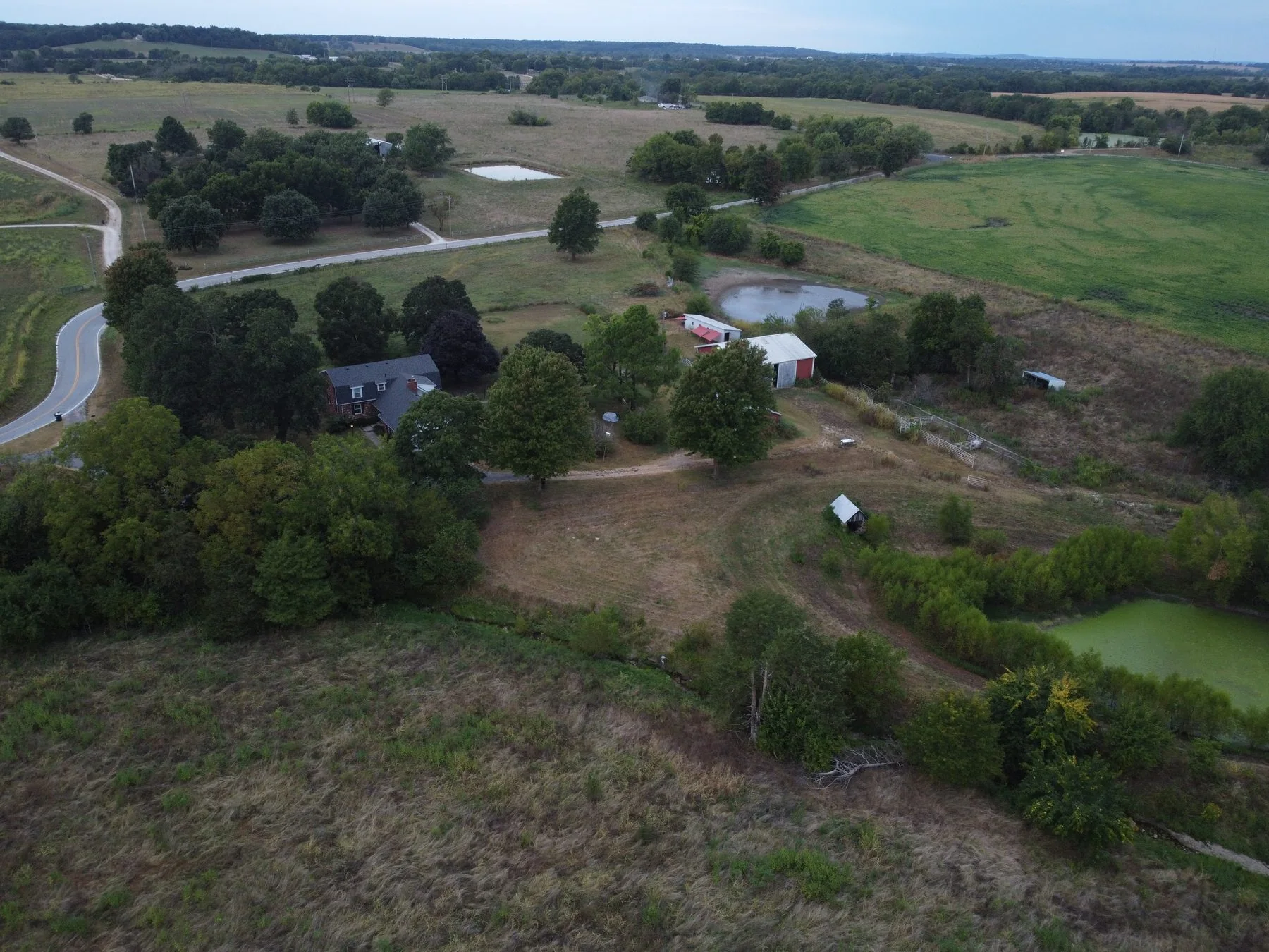 Aerial view of a rural property surrounded by fields, ponds, and winding roads