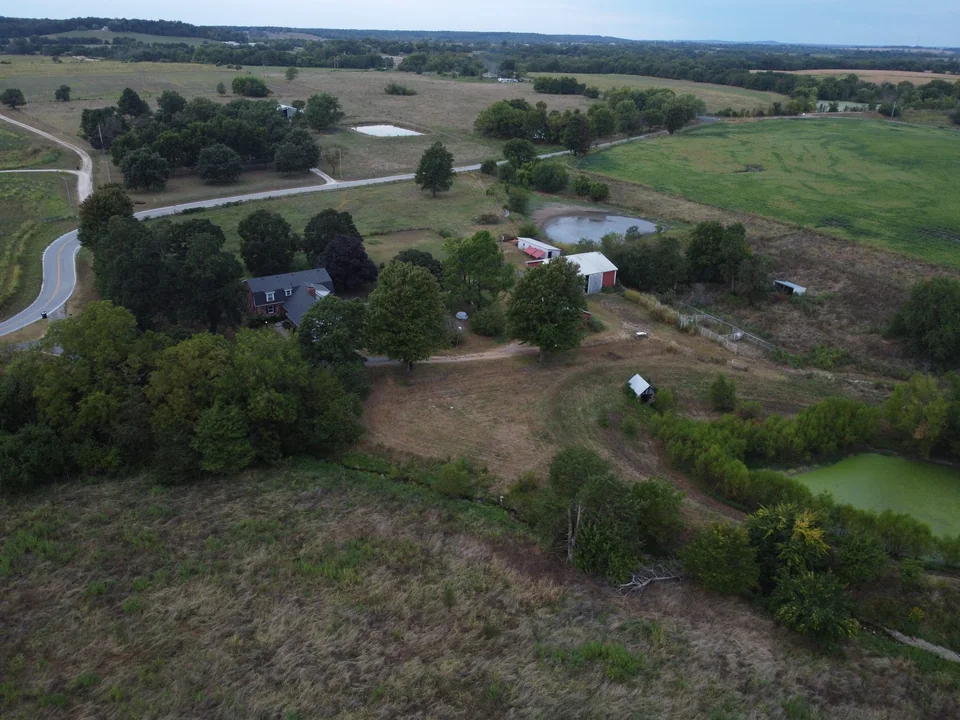 Aerial view of a rural property surrounded by fields, ponds, and winding roads