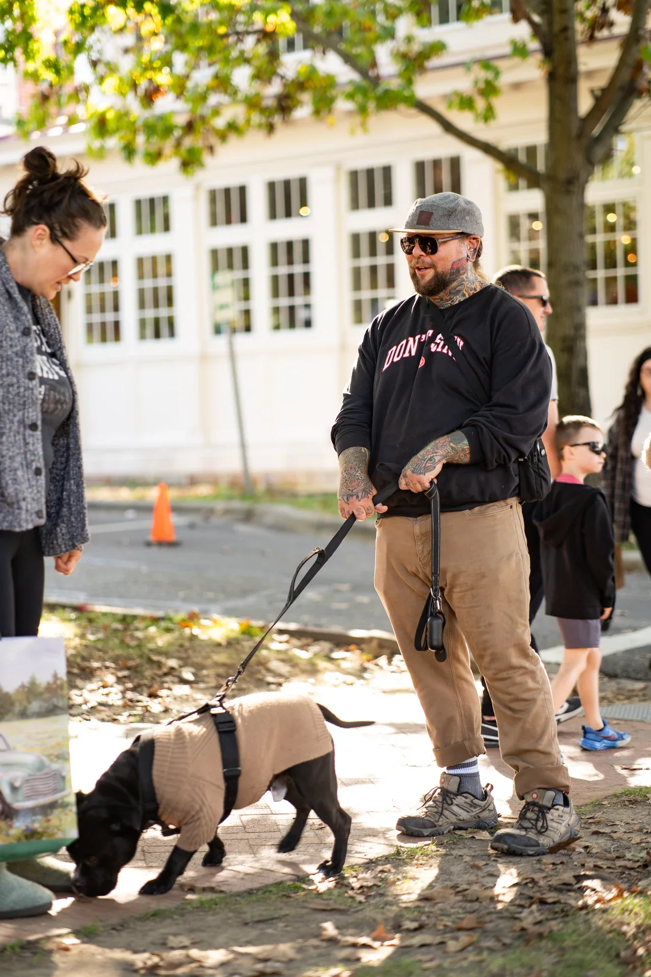 A person standing beside a leashed pig while another person looks on