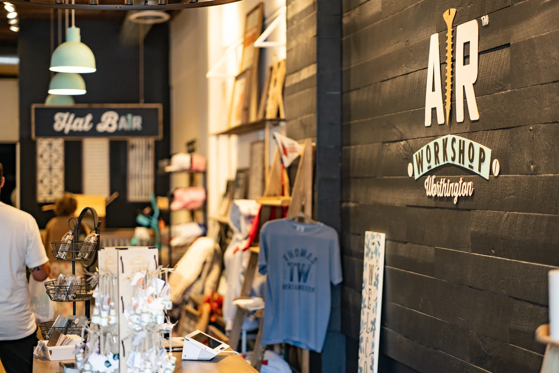 A warmly lit workshop entrance with a hat bar and retail displays