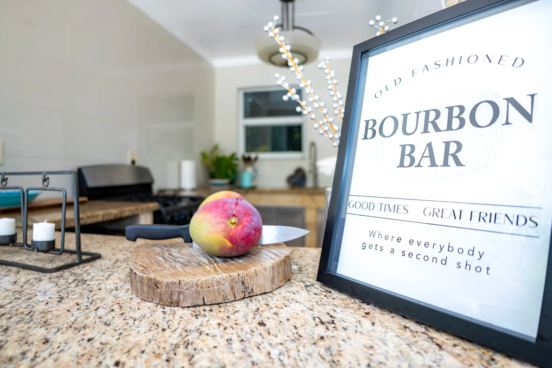 A framed bourbon-bar sign and small globe on a bright kitchen countertop