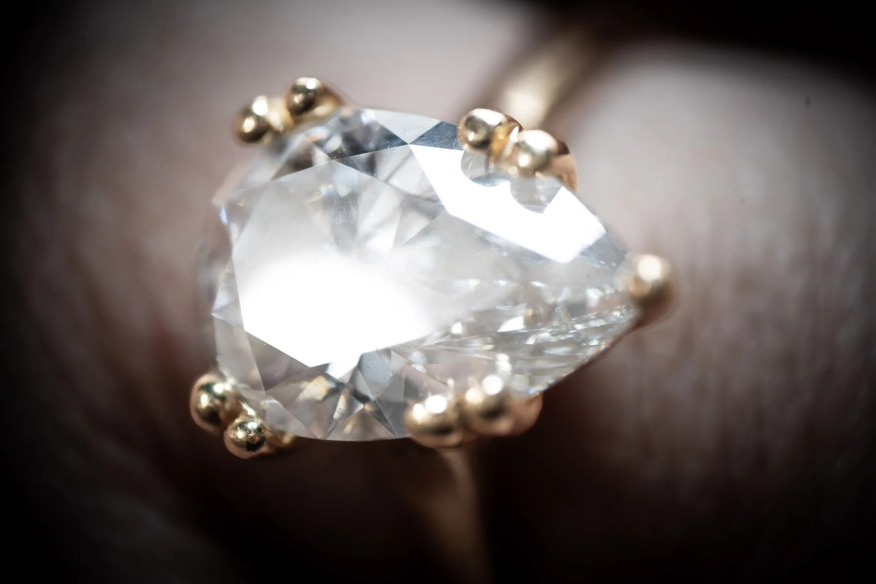 Extreme close-up of a clear faceted gemstone held by gold prongs