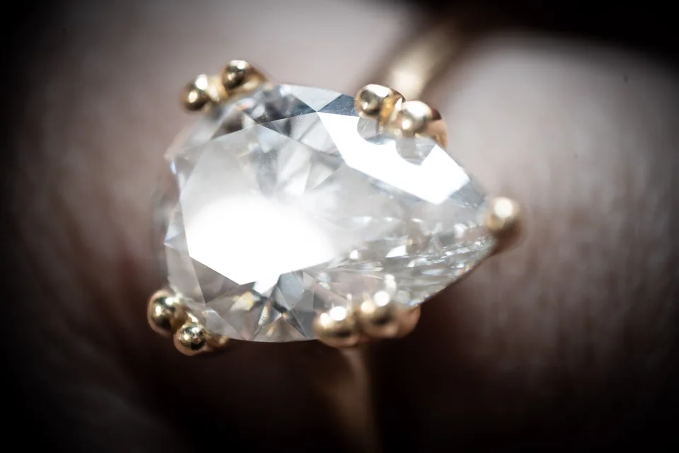 Extreme close-up of a clear faceted gemstone held by gold prongs