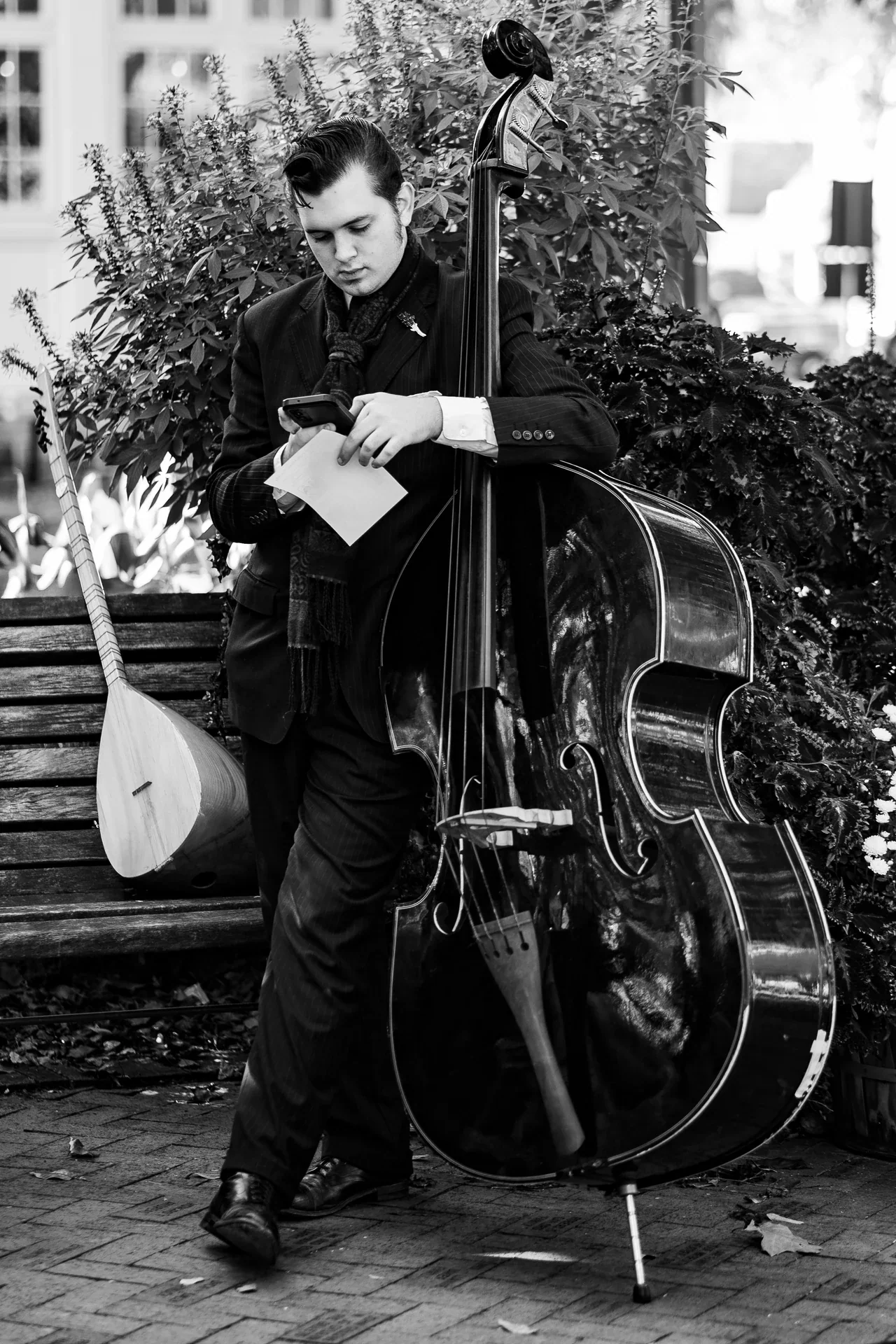 A musician standing beside an upright bass outdoors, in black and white