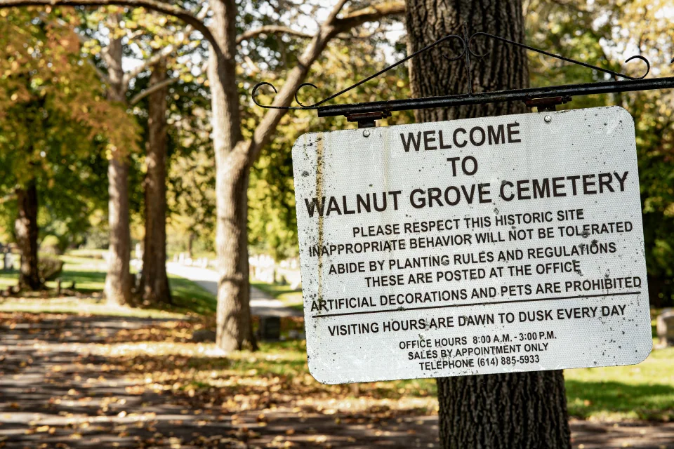 A sign for Walnut Grove Cemetery beneath autumn trees