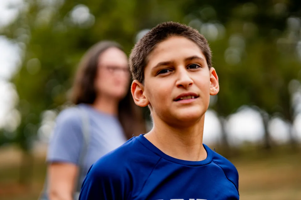A person in a blue shirt looking upward with another person softly blurred behind