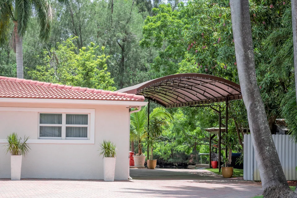 A light-colored outbuilding with a terracotta roof beside a covered walkway